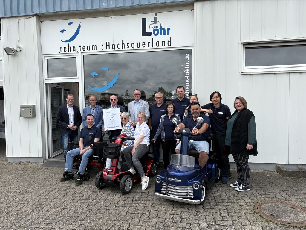 Manfred Löhr (hinten 3. v. li.) und Isolde Löhr (vorne, 2. v. li.) feiern gemeinsam mit Wirtschaftsförderer Thomas Becker, Bürgermeister Dr. Christof Bartsch, IHK-Teamleiter Stephan Britten (hinten v. li.) und ihren Mitarbeiterinnen und Mitarbeitern „75 Jahre Sanitätshaus Löhr.“ (Foto: Sanitätshaus Löhr)