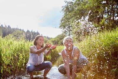 Zwei planschende Frauen an einem Gewässer in der Natur