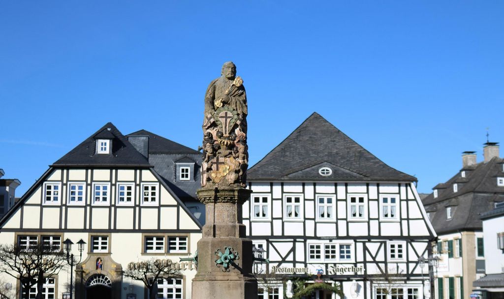 Petrusbrunnen / Kump auf dem Marktplatz Brilon mit Blick auf zwei Cafes / Fachwerkhäuser