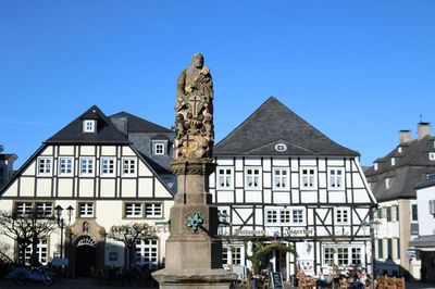 Petrusbrunnen / Kump auf dem Marktplatz Brilon mit Blick auf zwei Cafes / Fachwerkhäuser